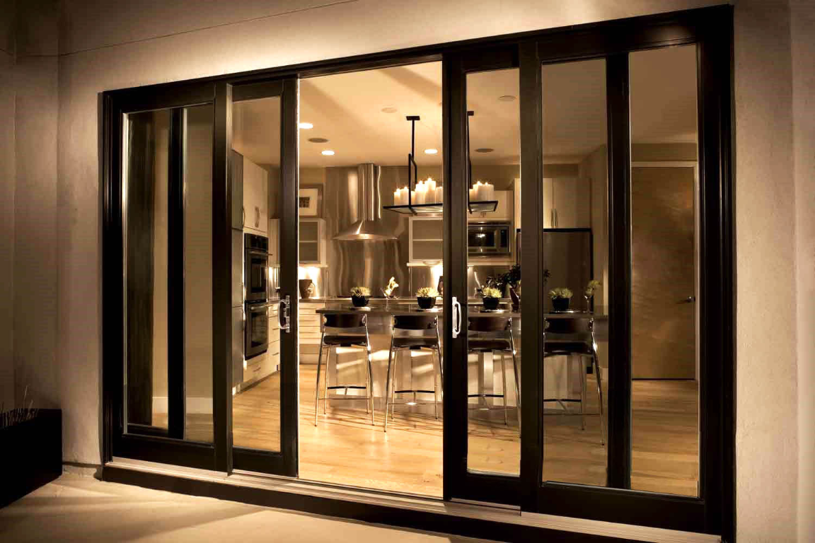 Black aluminium-framed sliding glass doors opening onto a warm, contemporary kitchen